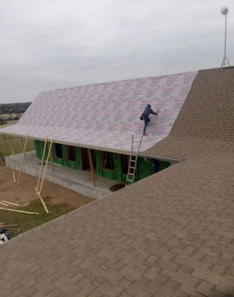 Worker preparing underlayment for a metal roof installation in Hanson